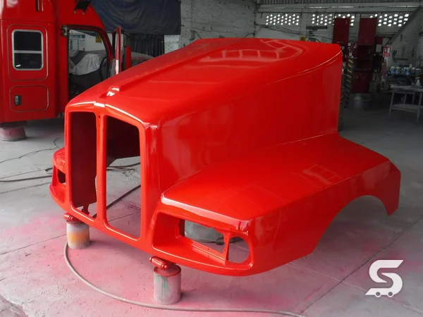 Cofre de tractocamión recién pintado en rojo durante el acabado de pintura — Talleres Saucedo, Uruapan, Michoacán